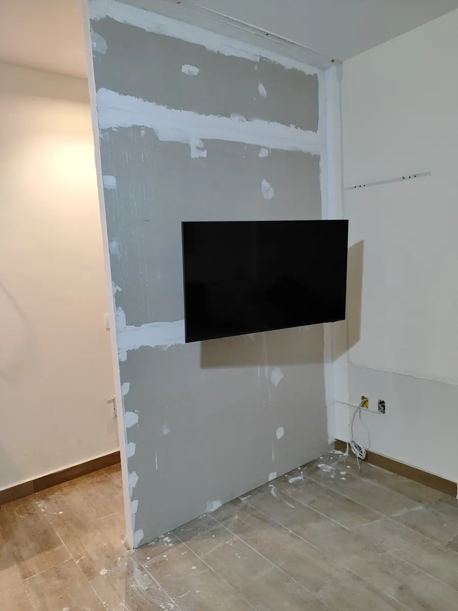 Parede de drywall com juntas tratadas e TV instalada